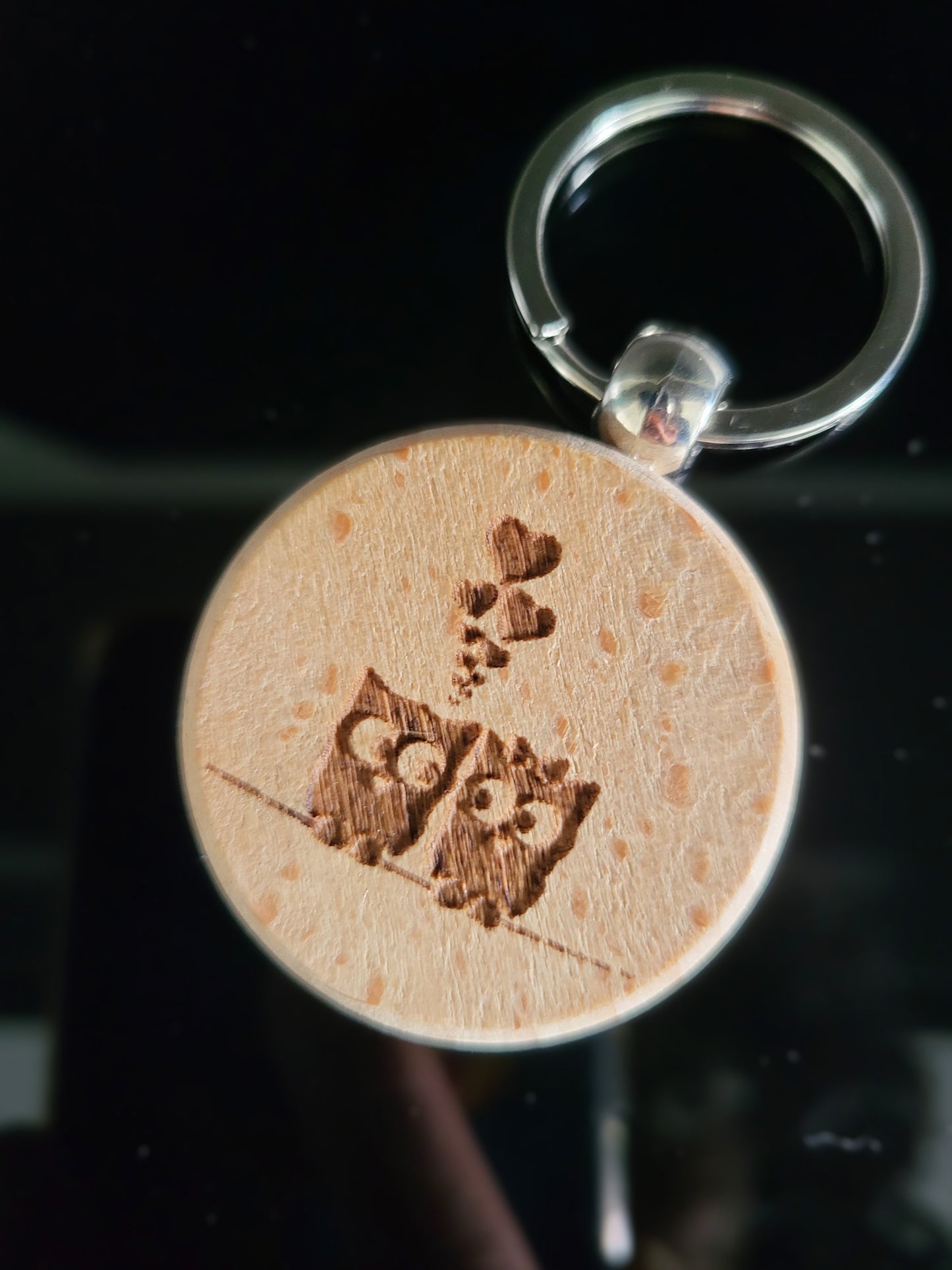 Runder Holz-Schlüsselanhänger mit Gravur zweier verliebter Eulen auf einem Ast und kleinen Herzmotiven. Liebevolles Accessoire aus Naturholz – ideal als Geschenk oder persönlicher Glücksbringer.