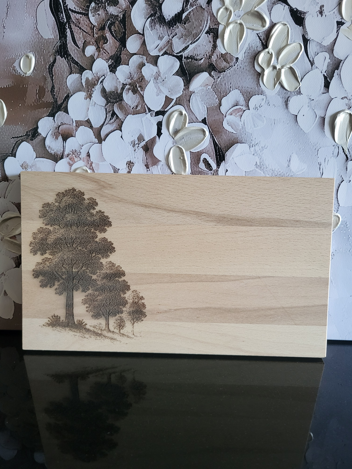 Schneide- oder Servierbrett aus Buchenholz mit einem Naturmotiv. Die Lasergravur zeigt eine Baumgruppe, die an einen Waldspaziergang erinnert. Ideal für Naturliebhaber oder als stilvolle Küchen- und Esszimmerdekoration.