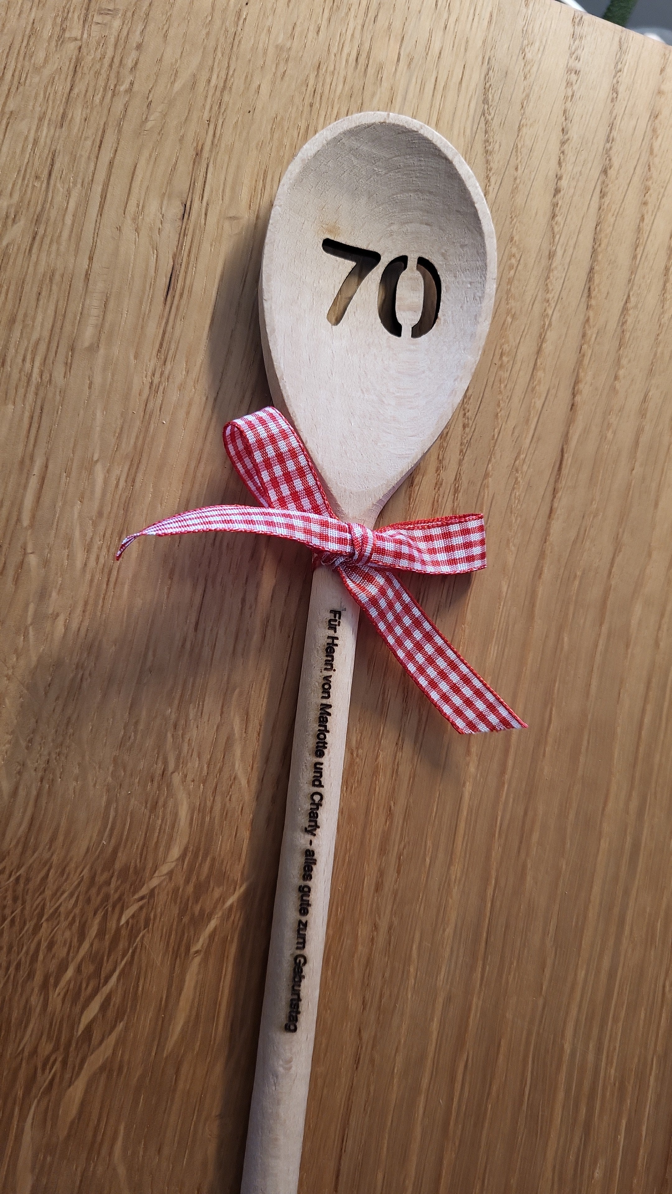 „Personalisierter Kochlöffel aus Holz mit Zahlenausschnitt ‚70‘ im Löffelkopf, Gravur am Stiel und roter Schleife – handgefertigt von ALPCUT. Originelles Geschenk zum 70. Geburtstag oder Jubiläum, dekorativ und praktisch zugleich. Nachhaltiges Naturholz, individuell gravierbar und ideal als persönliche Geschenkidee für besondere Anlässe.“