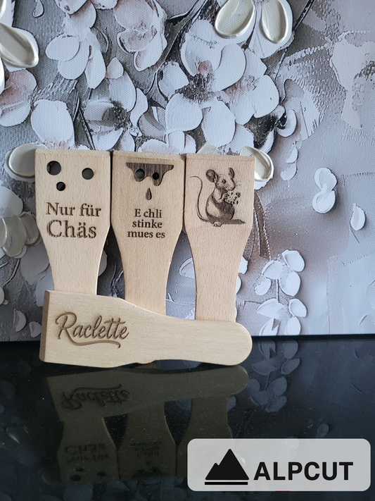„Racletteschaber aus Buchenholz mit Gravur – lustige Motive und Sprüche rund um Käse, Raclette und Schweizer Tradition. Handgefertigte Holzschaber mit personalisierten Designs wie Maus, Käselöcher oder witzige Sprüche. Perfektes Zubehör für Raclette-Abende, Fondues und als originelles Geschenk für Käseliebhaber – nachhaltig hergestellt von ALPCUT.“
