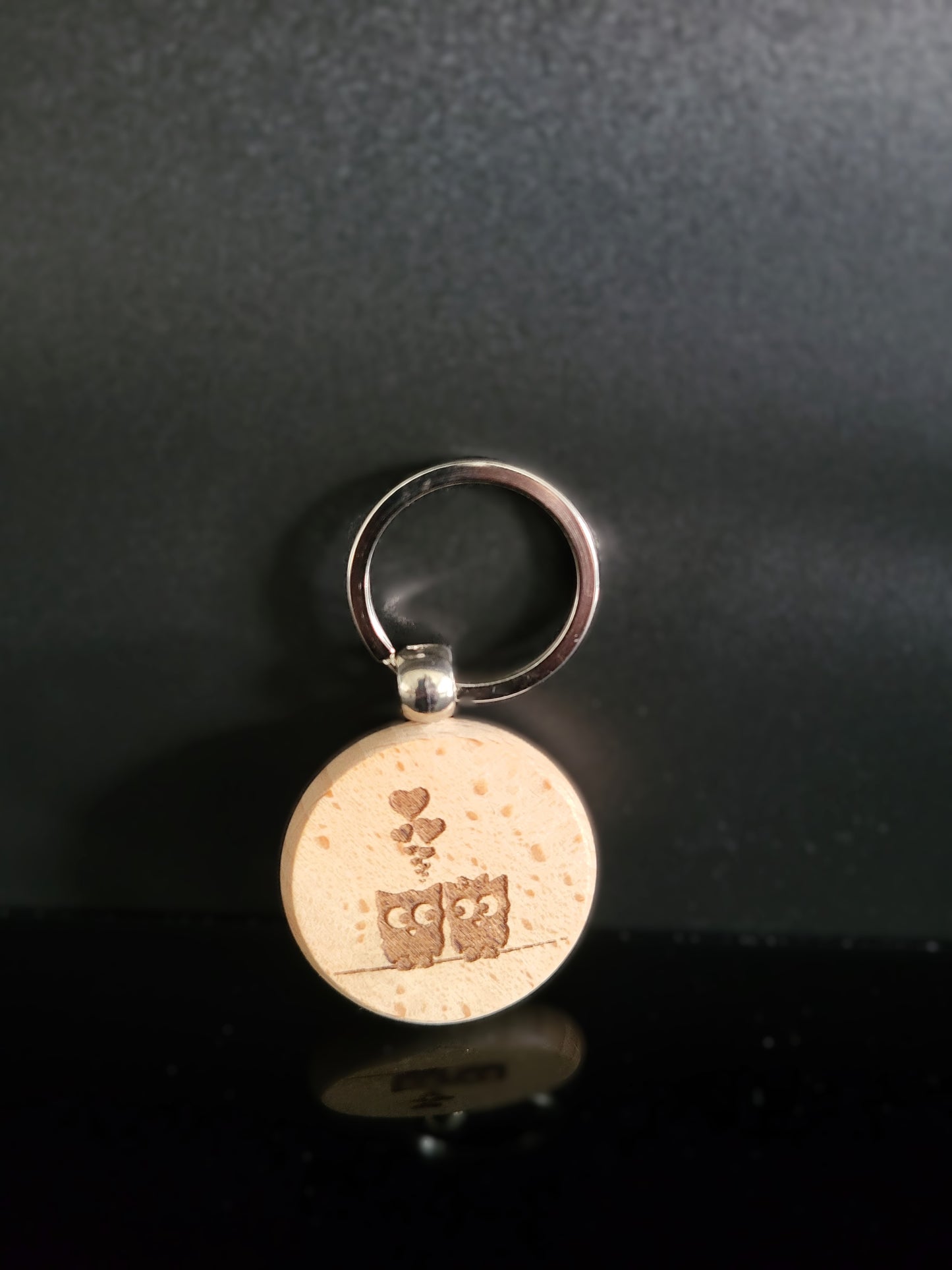 Runder Holz-Schlüsselanhänger mit Gravur zweier verliebter Eulen auf einem Ast und kleinen Herzmotiven. Liebevolles Accessoire aus Naturholz – ideal als Geschenk oder persönlicher Glücksbringer.