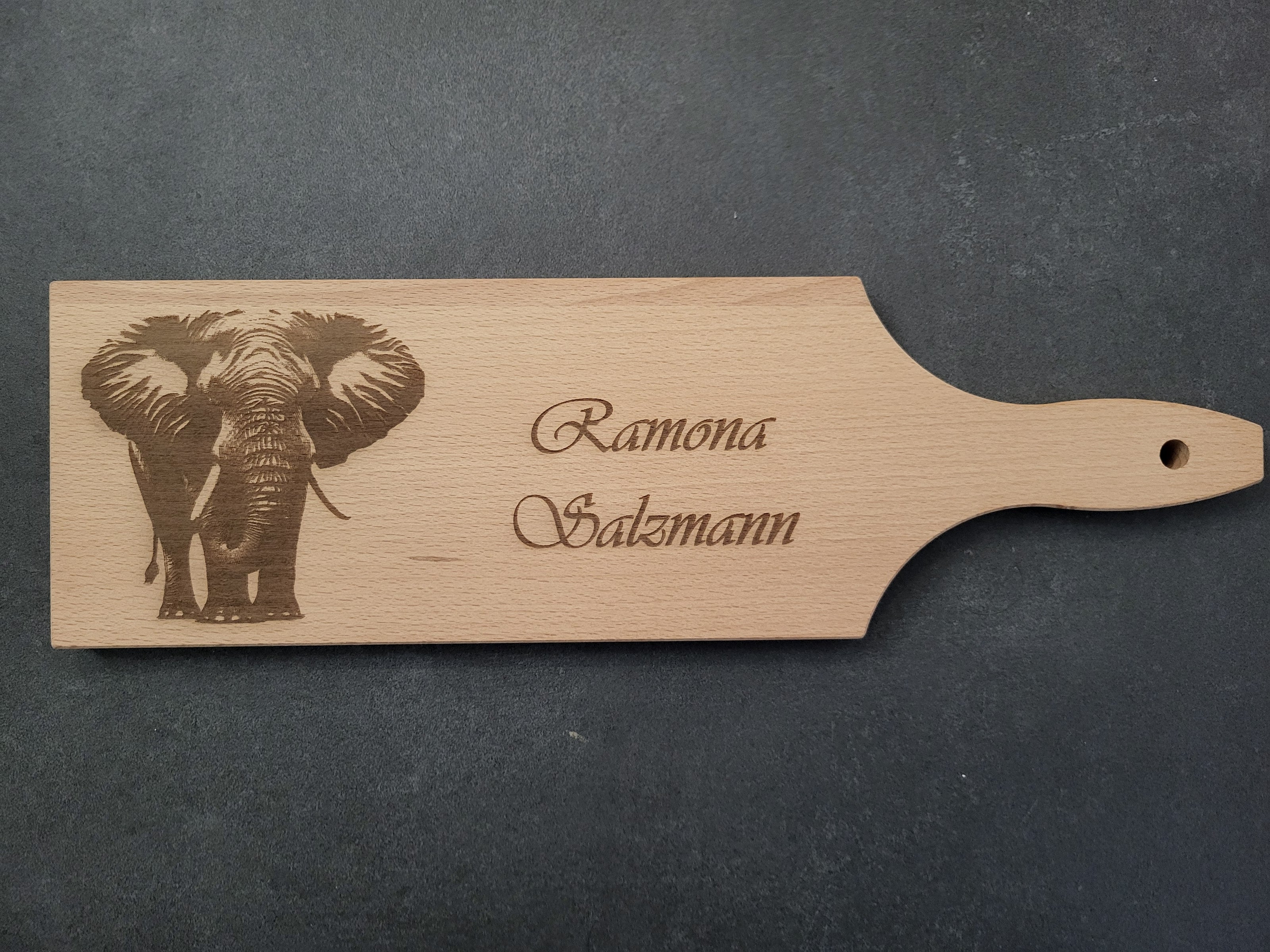 „Personalisierbares Schneidebrett aus hochwertigem Buchenholz mit detailreicher Elefant-Gravur – ideales Geschenk für Tierliebhaber oder besondere Anlässe wie Geburtstage, Jubiläen oder Einweihungen. Das Holzbrett mit individuellem Namen vereint natürliche Schönheit und Funktionalität und wird in der Schweiz mit viel Liebe zum Detail gefertigt.“