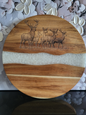 Rundes Schneidebrett aus Akazienholz mit weisser Epoxidharz-Einlage und detailreicher Gravur einer Hirschfamilie, handgefertigt von ALPCUT – dekoratives Servierbrett und praktisches Küchenaccessoire im alpinen Design, ideal als Geschenk für Naturfreunde und Wildtierliebhaber.
