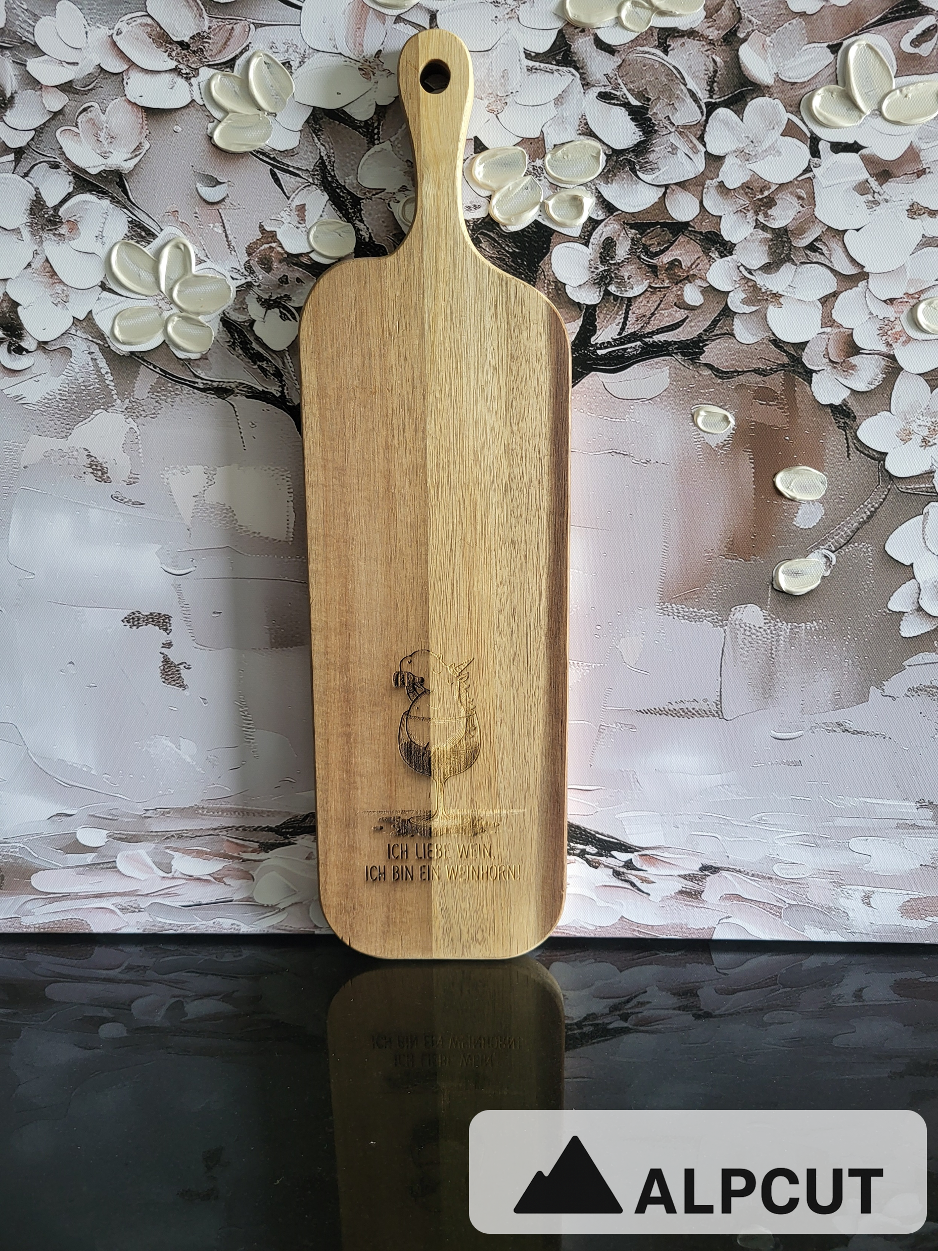 „Servier- und Schneidebrett aus Akazienholz mit Gravur Weinglas und Spruch ‚Ich liebe Wein, ich bin ein Weinhorn‘ – handgefertigt von ALPCUT. Edles Holzbrett mit natürlicher Maserung, ideal als Käsebrett, Apérobrett oder Geschenk für Weinliebhaber. Nachhaltiges Naturholz, hochwertig verarbeitet und mit humorvoller Gravur, perfekt für gesellige Abende.“
