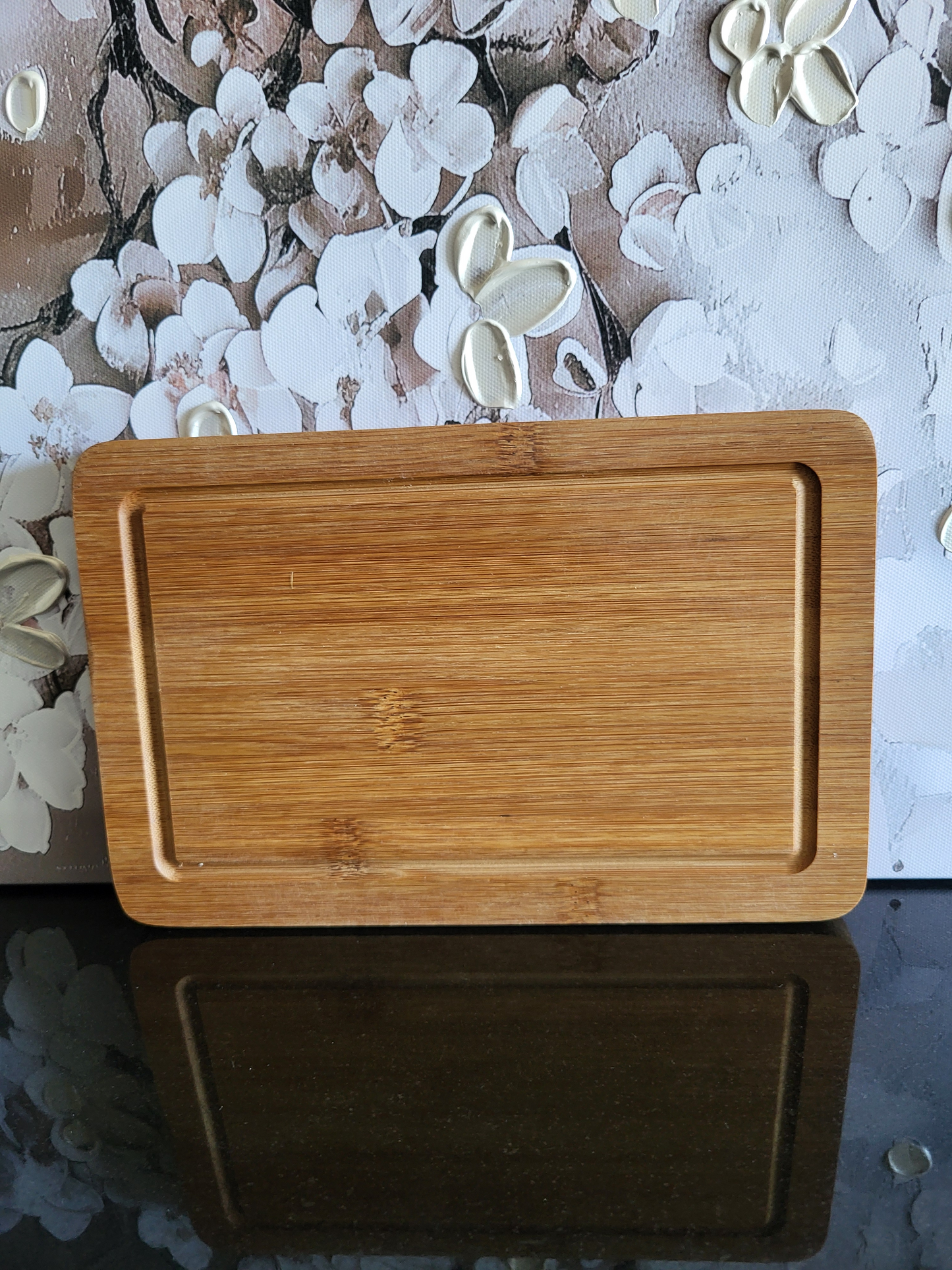 Wendenbares Schneidebrett aus Bambus mit Blumen-Gravur. Die Vorderseite ziert ein kunstvolles Motiv, während die Rückseite eine praktische Saftrinne hat. Ideal als Küchenbrett, Servierplatte oder Schneideunterlage. Perfekt für die Zubereitung von Speisen, die viel Saft abgeben.