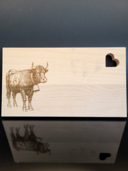 Schneidebrett aus Schweizer Buchenholz mit feiner Gravur einer Eringerkuh und herzförmiger Aussparung. Natürliches, nachhaltiges Holzbrett von AlpCut – ideal als Geschenk, Servierbrett oder Dekoration.
