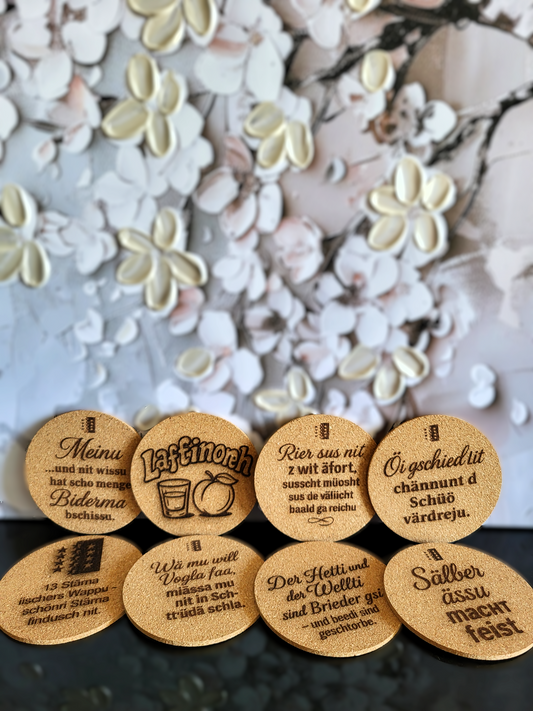 Eine Kollektion handgefertigter Kork-Untersetzer von Alpcut, lasergraviert mit einer Vielzahl von humorvollen und traditionellen Sprüchen im Walliser Dialekt, darunter Zitate zum Walliser Wappen, zur Abricotine und bekannten Mundart-Sprichwörtern.